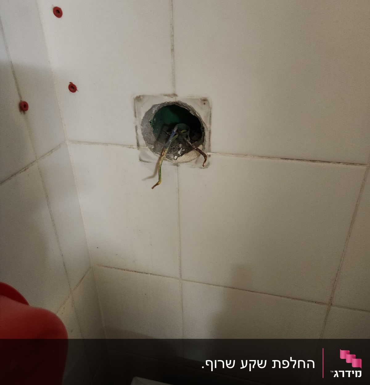 חוטי חשמל יוצאים מקיר אריחים לבן